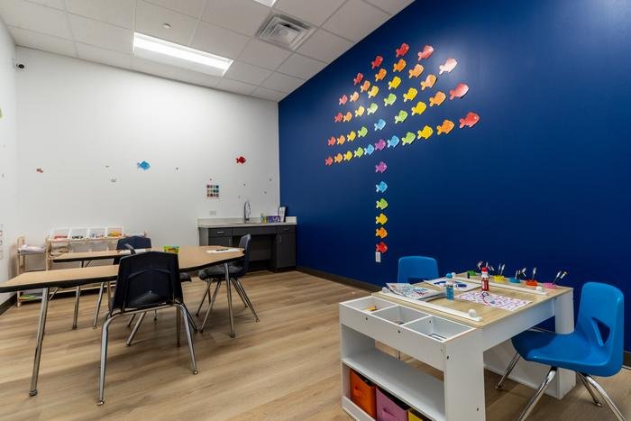 The art room at SOS McKinney: work tables, a sink, brushes and paints, and a wall of paper fish in rainbow colours.