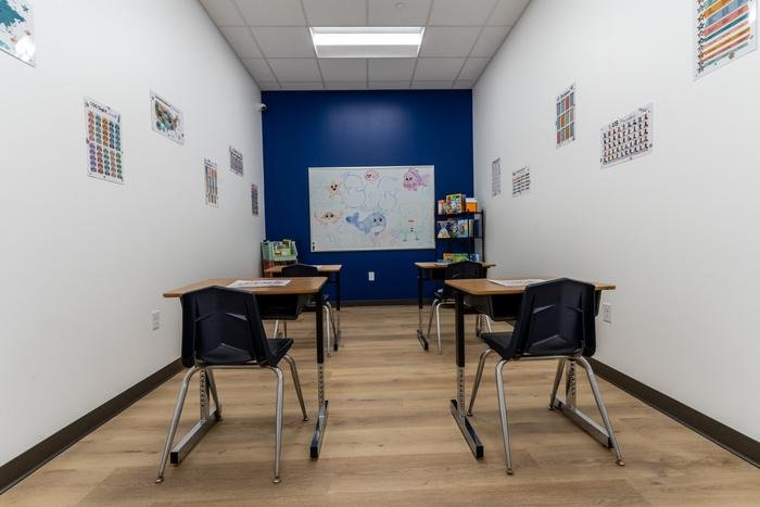 The mock classroom at SOS McKinney: four school desks facing a whiteboard, with sight words, a US map and a number chart on the walls.