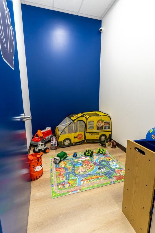 A stateroom with a pop-up school bus tent, toy vehicles and a town play mat, used for pretend play and early social skills.
