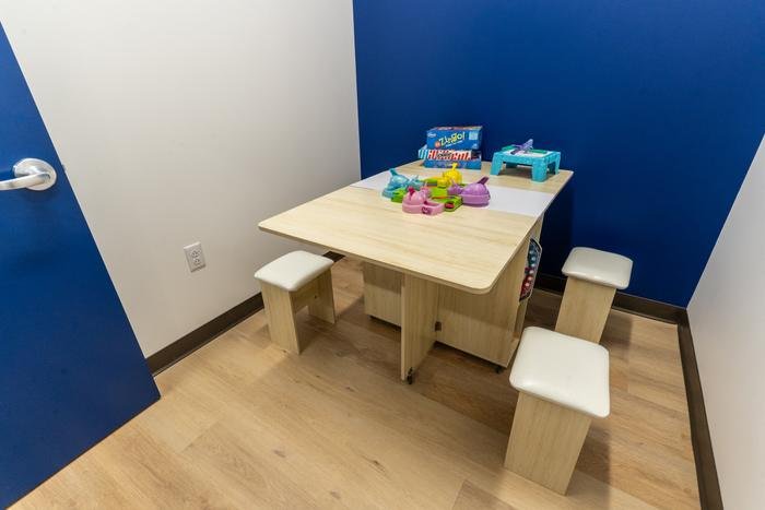 A small therapy room with a work table, stools and board games ready on the table top.